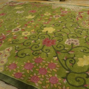 Low-pile lime green rug featuring a dense scrolling floral pattern in pink and yellow on wood flooring.
