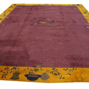 Plum field rug with a wide mustard yellow border featuring detailed floral and potted plant motifs.