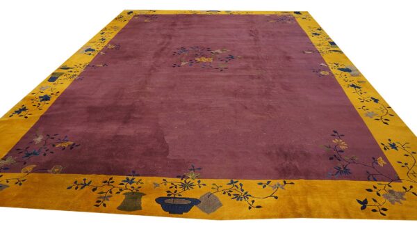 Plum field rug with a wide mustard yellow border featuring detailed floral and potted plant motifs.