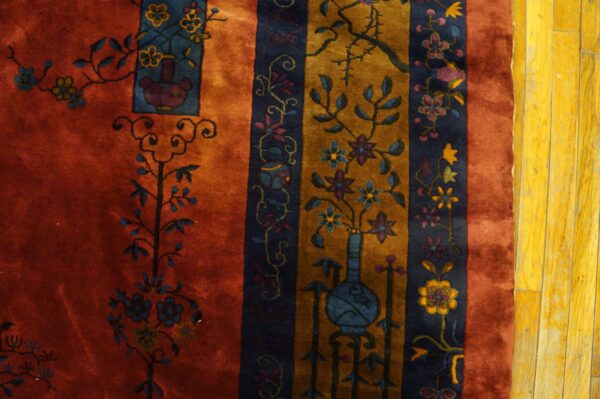 Rust, gold, and dark blue striped rug with ornate floral and botanical patterns on yellow wood floors.