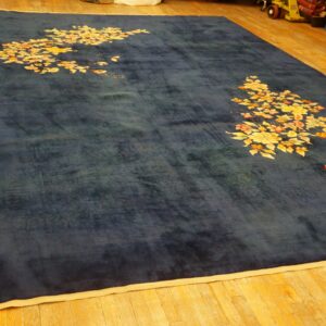 Dark blue rug with corner clusters of yellow and orange flowers on a wood floor.