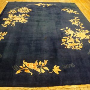Navy blue rug with large golden floral patterns and subtle geometric accents on wood floor.