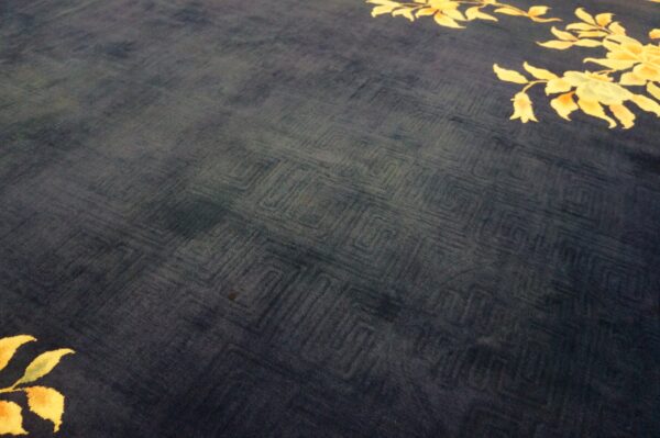 Navy blue plush rug with a tone-on-tone carved geometric background and bright yellow floral motifs.