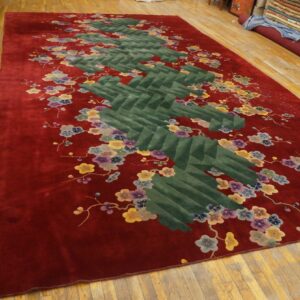Deep red plush rug featuring a segmented green zigzag pattern accented by multicolored floral branches.