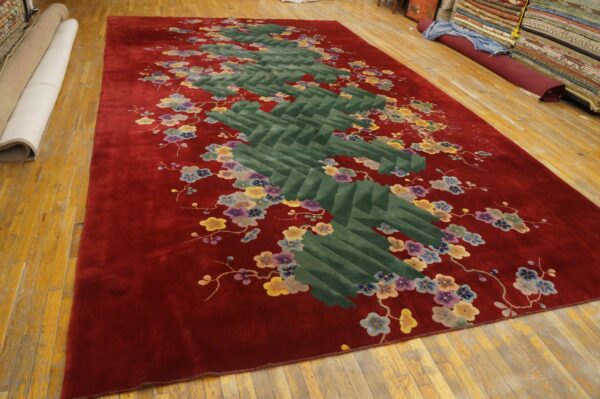 Deep red plush rug featuring a segmented green zigzag pattern accented by multicolored floral branches.