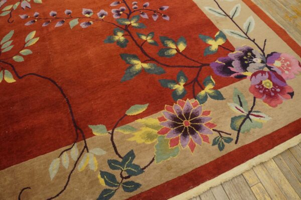 Rust and beige border rug featuring large purple, pink, and green stylized flowers on wood floor.