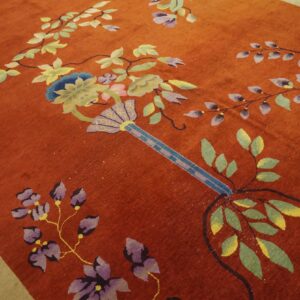 Rust-colored rug with a large-scale, colorful floral vine pattern and a pale beige border.