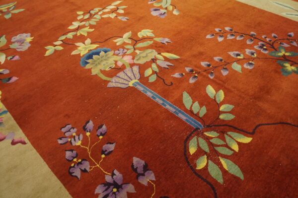 Rust-colored rug with a large-scale, colorful floral vine pattern and a pale beige border.
