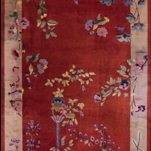 Plush red rug featuring a large, colorful floral and vine design across the field and wide tan border.