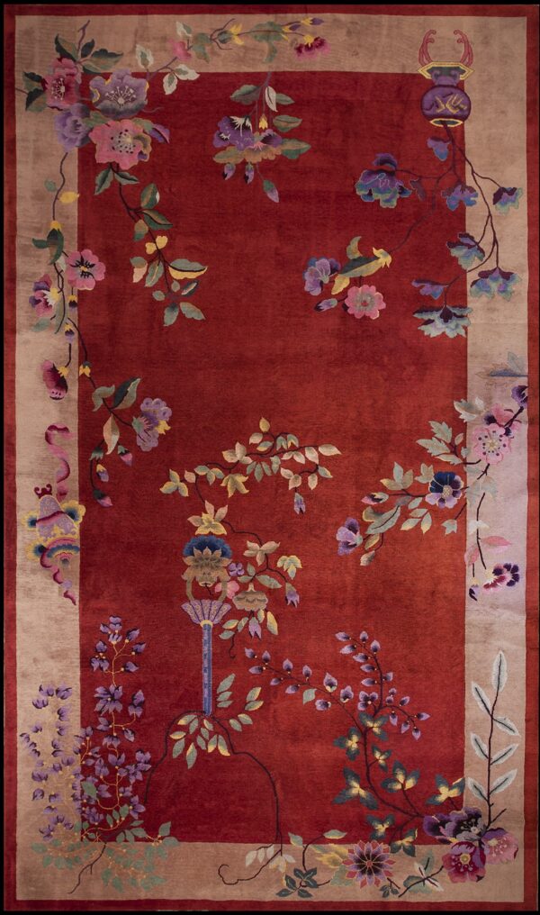 Plush red rug featuring a large, colorful floral and vine design across the field and wide tan border.