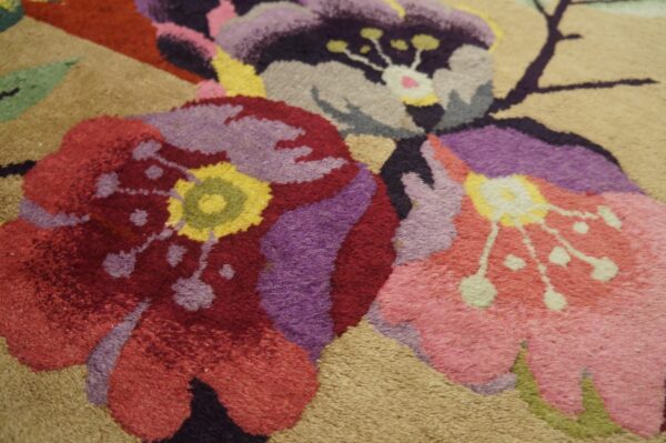 Close-up of a plush rug featuring large red, purple, and pink floral designs on a light beige background.