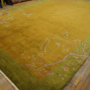 Gold oriental rug with floral and vine patterns, featuring a wide green border on hardwood floors.