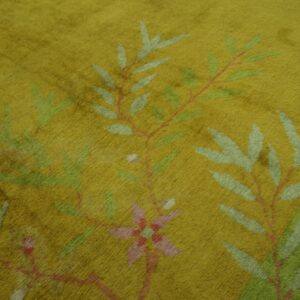 Close-up of a high-pile chartreuse rug with a dense pattern of stylized green and pink botanical branches.
