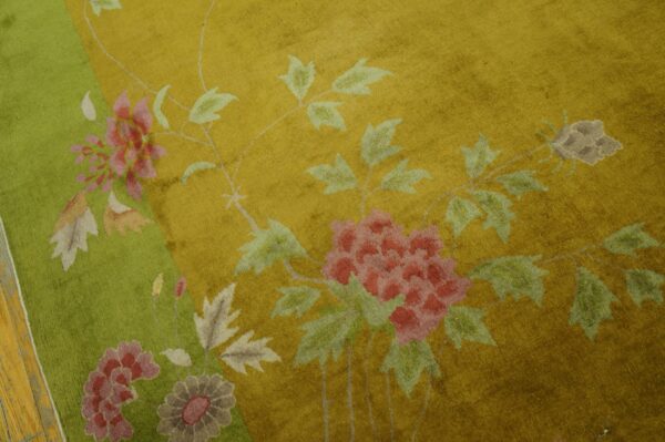 Plush gold rug with a lime green border and large pink and gray floral motifs.