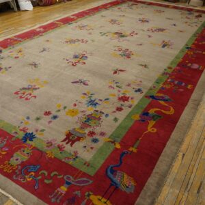 Oversized beige rug with detailed multicolored floral and bird patterns bordered in red on wood floors.