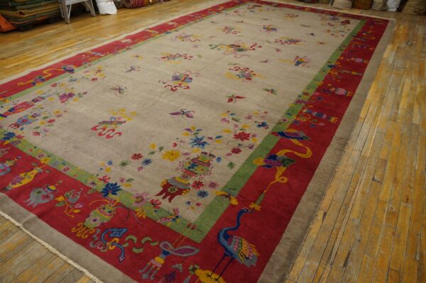 Oversized beige rug with detailed multicolored floral and bird patterns bordered in red on wood floors.
