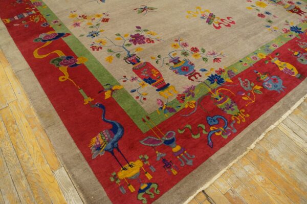 Multicolored rug corner with a beige field, floral vases, and a wide red border showing a crane on wood floor.
