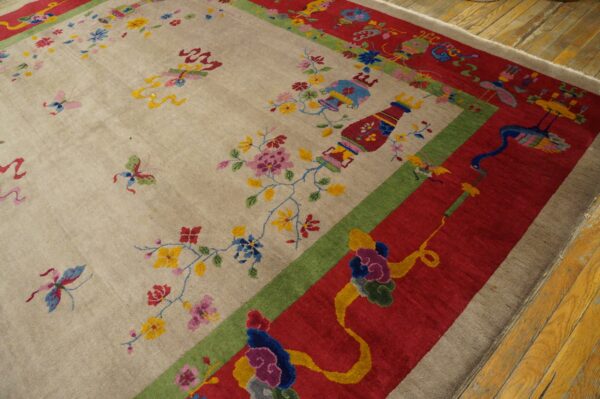 Beige rug with colorful floral, vase, and butterfly patterns, framed by wide red and green borders on wood floor.