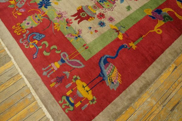 Diagonal view of a tan, red, and green rug featuring a colorful crane motif on rustic wood floors.