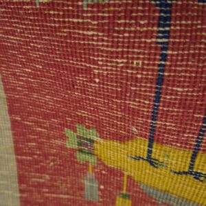 Textured, flat-woven rug detail features geometric patterns in red, yellow, beige, green, and blue.