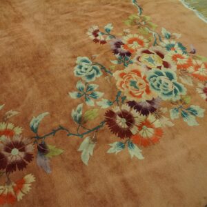 Plush rust colored rug with an elaborate multicolor floral pattern rests on distressed wood planks.