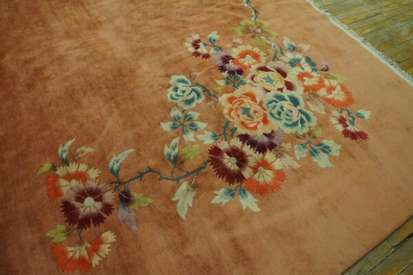 Plush rust colored rug with an elaborate multicolor floral pattern rests on distressed wood planks.