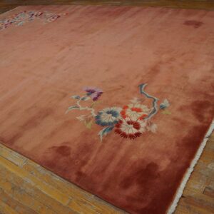 High pile rose rug with blue and red floral accents rests on patchy wood flooring.