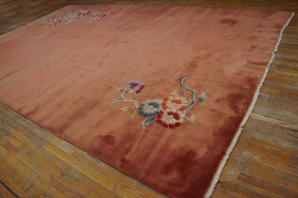 High pile rose rug with blue and red floral accents rests on patchy wood flooring.