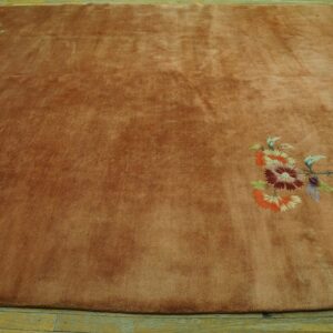 Large rust-colored plush rug featuring bright floral designs diagonally across a light wood floor.