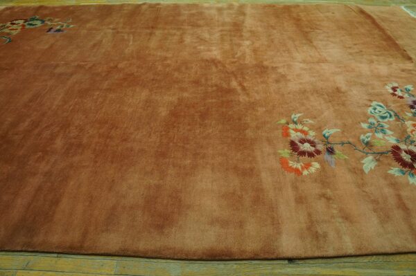 Large rust-colored plush rug featuring bright floral designs diagonally across a light wood floor.