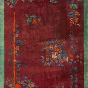 A deep maroon rug with a wide teal border and detailed multicolored floral patterns.
