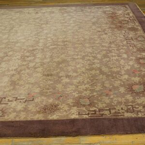 Muted brown rug with delicate beige floral pattern and dark brown border on distressed wood flooring.