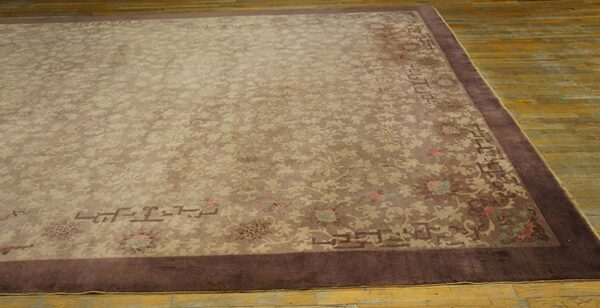 Muted brown rug with delicate beige floral pattern and dark brown border on distressed wood flooring.