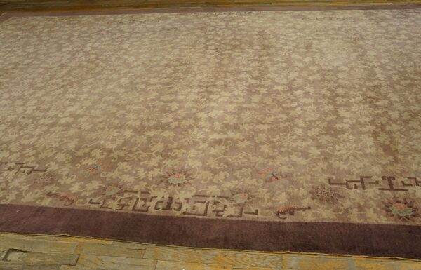 Muted brown rug with an all-over beige floral pattern and a dark plum border on distressed wood flooring.