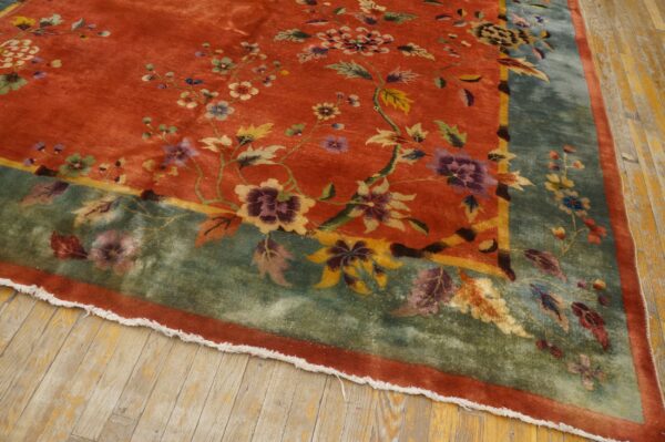 High-pile orange rug with purple and yellow floral vines, framed by a broad sage border on wood flooring.