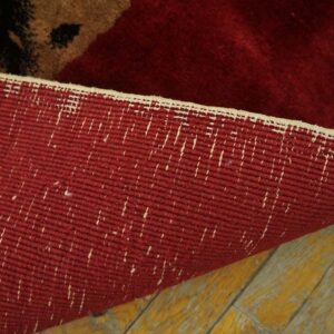 The woven red backing of a high-pile rug is visible as it rests on distressed yellow wooden planks.