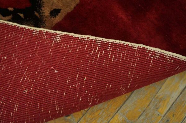 The woven red backing of a high-pile rug is visible as it rests on distressed yellow wooden planks.
