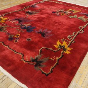 Vibrant red rug on wood floor featuring a detailed vine border and colorful floral and leaf pattern.