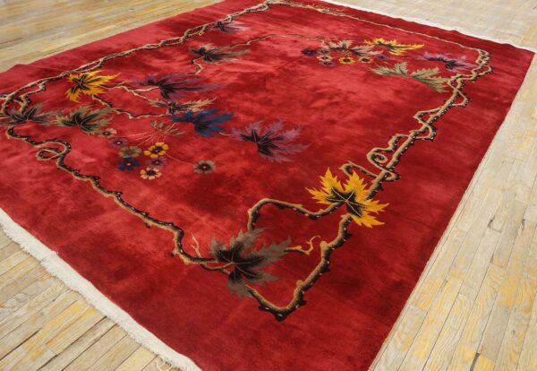 Vibrant red rug on wood floor featuring a detailed vine border and colorful floral and leaf pattern.