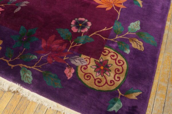 Deep purple rug displaying large floral and vine motifs in orange, teal, and gold on light wood flooring.