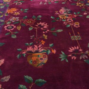 High pile rug with a deep magenta field and purple border, decorated with multicolored blossoms and vines on wood floor.