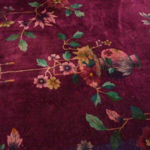 Plush plum rug detail showing stylized pink and teal flowers, green vines, a vase, and a knot design.