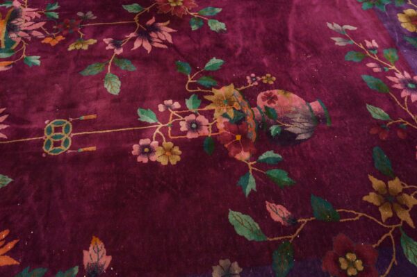 Plush plum rug detail showing stylized pink and teal flowers, green vines, a vase, and a knot design.