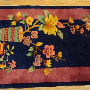 Navy rug with a wide mauve border featuring a central floral and vase design on light wood flooring.