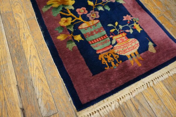 Colorful floral rug on navy ground with a thick mauve border rests on weathered wood planks.
