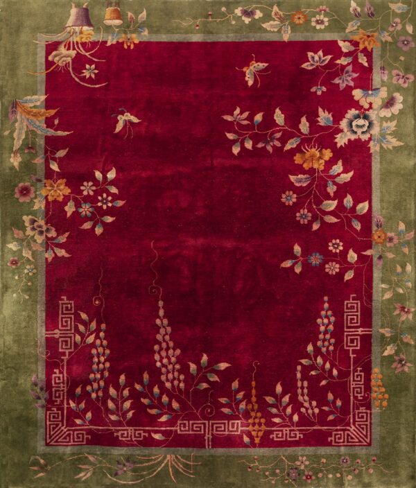 Velvety deep crimson rug with an olive green border and scrolling stylized floral and butterfly patterns.
