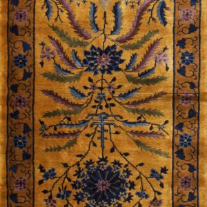 Mustard yellow rug with a central vase design and dense stylized foliage in blue, purple, and green.