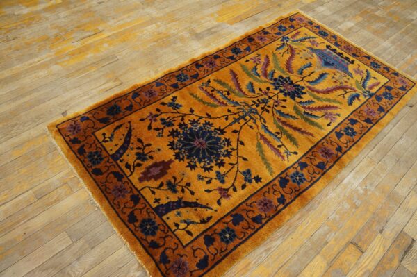 A high-pile gold rug with dark blue and rust traditional patterns rests on distressed wooden floorboards.