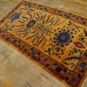 A golden yellow rug with navy and maroon floral designs rests on weathered wooden floorboards.