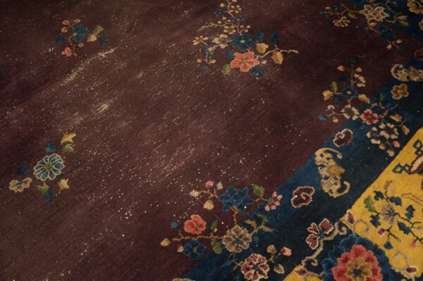 Deep purple rug detail showing distressed floral pattern and sections of dark blue and bright yellow.